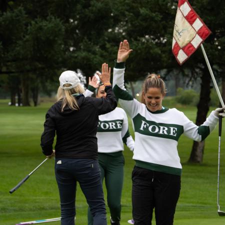 Two golfers high five-ing